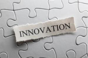Torn paper strip reading INNOVATION laid over a jigsaw puzzle backdrop
