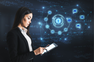 Businesswoman in a black blazer uses a tablet to interact with a holographic network of cloud and data icons.
