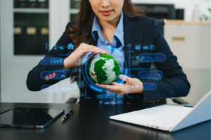 Businesswoman holding a glowing holographic globe with digital sustainability icons around it, symbolizing environmental technology and data-driven eco initiatives